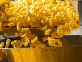 A machine actively producing yellow macaroni, showcasing the automated process of pasta production in a factory setting.