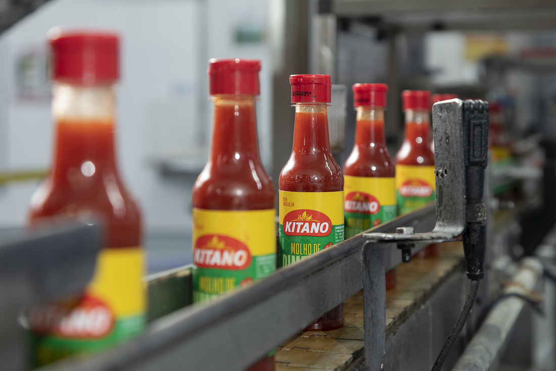 General Mills Brazil- Image showing a production line with labeled and capped bottles of Kitano hot sauce, prepared for distribution.